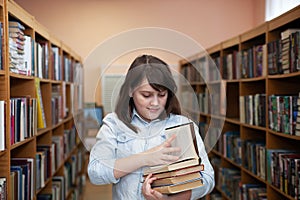 Teen girl taking   book from bookshelves in library, choosing