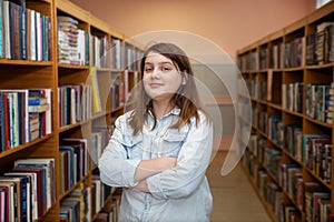 Teen girl taking   book from bookshelves in library, choosing