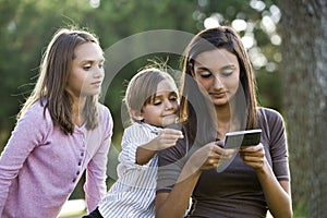 Teen girl texting, younger siblings watch