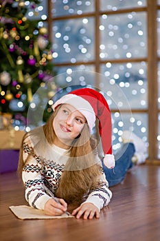 Teen girl thinking what to write in a letter to Santa Claus