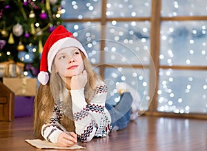 Teen girl thinking what to write in a letter to Santa Claus