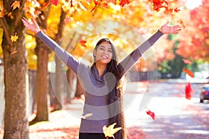 Teen girl throwing colorful autumn leaves in air under trees