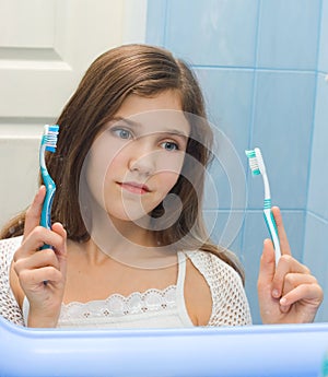 Teen girl to decide between the two toothbrushes photo