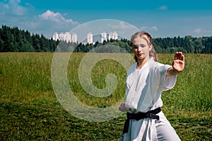 Teen girl training karate kata outdoors, performing a strike oi zuki