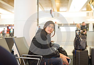 Teen girl traveller  waiting at airport for flight with luggage