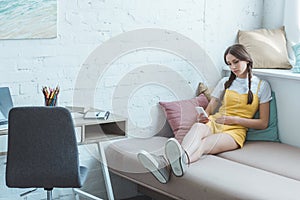teen girl using smartphone and sitting on sofa photo