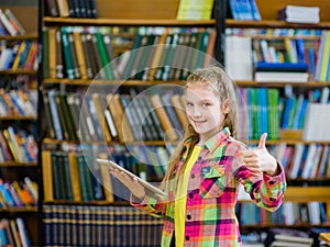 Teen girl using a tablet computer in a library and showing thumb
