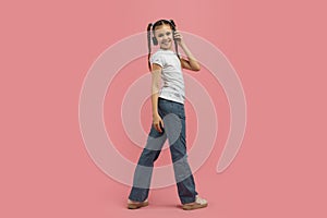 Teen girl walking with headphones on pink