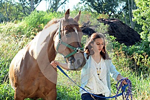 A teen girl walks with her horse