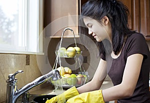 Teen girl washing dishes in kitchen photo