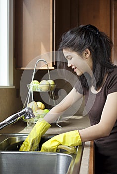 Teen girl washing dishes at kitchen sink
