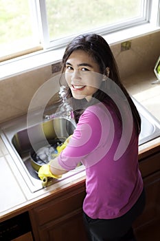 Teen girl washing dishes at kitchen sink
