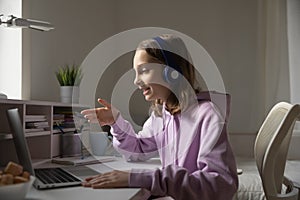 Teen girl wears headphones conference calling studying with online tutor photo