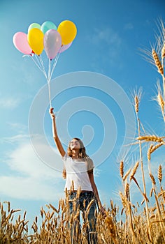 Teen girl at a wheat field with balloons