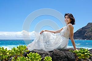 Teen girl in white dress on lava rock in Hawaii