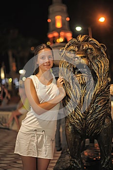 Teen girl in white dress next to the sculpture of a lion