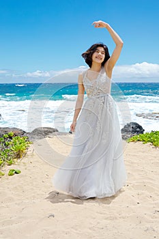 Teen girl in white dress twirling on Hawaiian beach