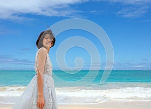 Teen girl in white dress walking barefoot on hawaiian beach