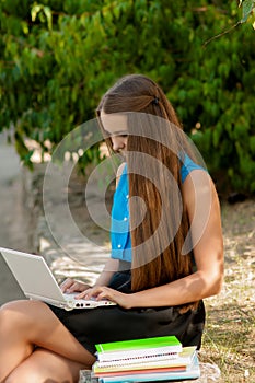 Teen girl works with the laptop in headphones and books