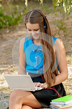 Teen girl works with the laptop in headphones and books