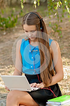 Teen girl works with the laptop in headphones and books