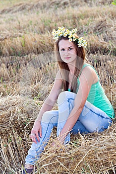 Teen girl with a wreath of daisies in field