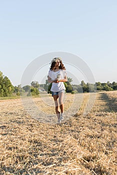 Teen girl in a wreath of daisies walketh in field