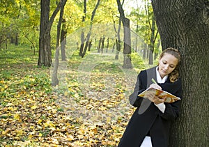 Teen girl writes a poetry in autumn park photo
