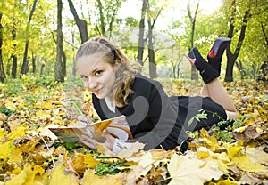 Teen girl writes poetry in copybook in autumn park