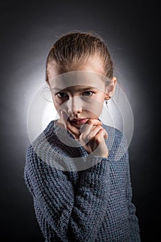 Teen girl 9-12 years old, looks into the frame, emotional studio portrait on a gray background