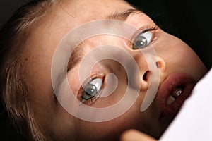 Teen girl 9-12 years old, looks into the frame, emotional studio portrait on a gray background