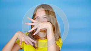 Teen girl in a yellow t-shirt is gesticulating with her hands, fooling around