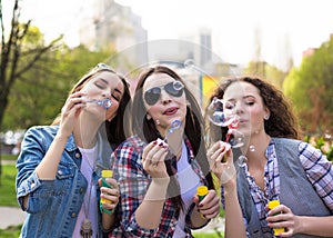 Teen girls blowing soap bubbles. Young happy teenagers having fun in summer park.