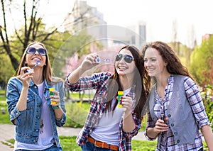 Teen girls blowing soap bubbles. Young happy teenagers having fun in summer park.