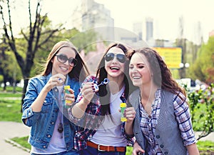 Teen girls blowing soap bubbles. Young happy teenagers having fun in summer park.