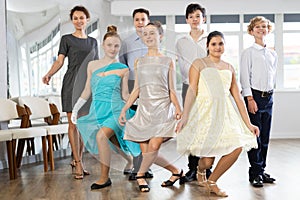 Teen girls curtsy and pose with ballroom dancing boys partners for reporting shot