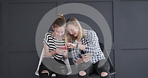 Teen girls discussing while using social media app on mobile phones