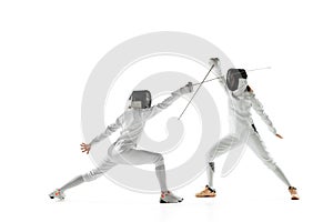 Teen girls in fencing costumes with swords in hands isolated on white background