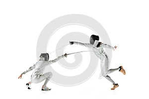 Teen girls in fencing costumes with swords in hands isolated on white background photo