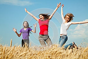 Teen girls jumping at a wheat field