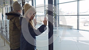 Teen girls is waiting their flight looking at panoramic window in airport terminal.