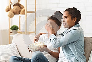 Teen girls watching horror on TV at home at daytime