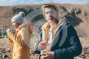 Teen guy drinking tea or coffee in mountains with friends