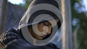 Teen guy feeling himself helpless, upset with bullying, hiding on backyard