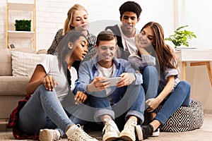 Teen guy showing new video on cellphone to friends