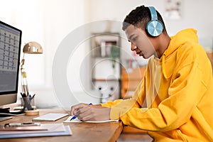 Teen guy studying at home with headphones on