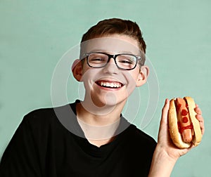 Teen handsome boy in myopia glasses with hot dog