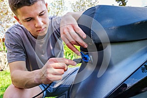 Teen inserts plug into charging socket of electric scooter