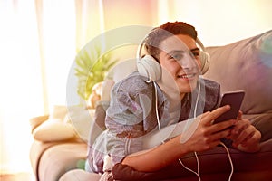 Teen listening music with headphones lying face down multicolored lights