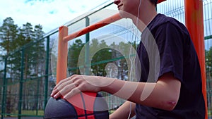 Teen listens to music on the basketball court.